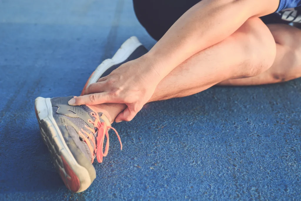 asian man use hands hold his ankle while running road park