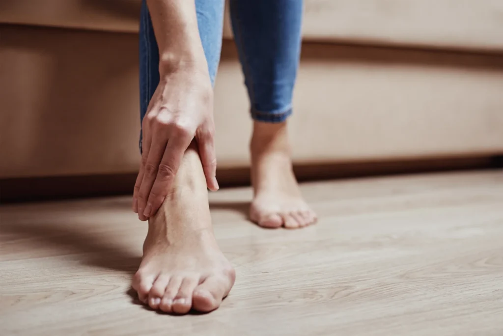 barefoot woman with light hair holding her foot 2026 03 24 00 32 15 utc