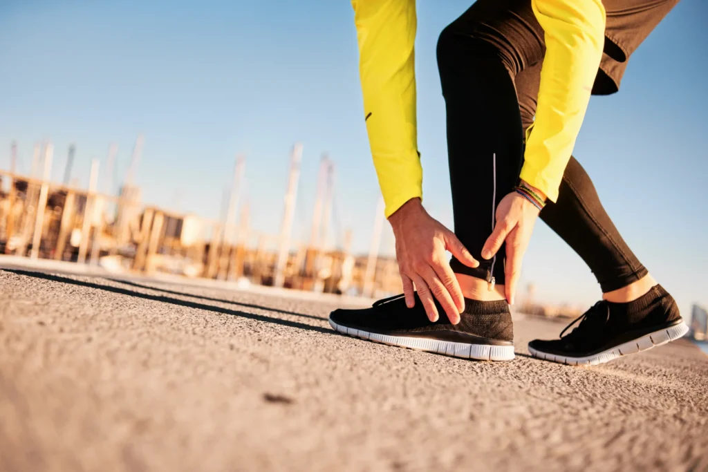 man stretching ankle on sidewalk near harbor 2026 03 26 05 05 26 utc